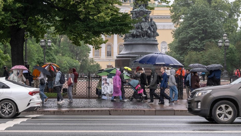 Невский проспект. Петербург накрыл очередной циклон. Прохожие в дождевиках или с зонтиком в руке идут по тротуару в центре города. Невский проспект. Петербург накрыл очередной циклон. Прохожие в дождевиках или с зонтиком в руке идут по тротуару в центре города.