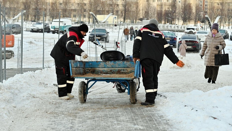 Сотрудники коммунальных служб посыпают тротуар песком с солью. Сотрудники коммунальных служб посыпают тротуар песком с солью.