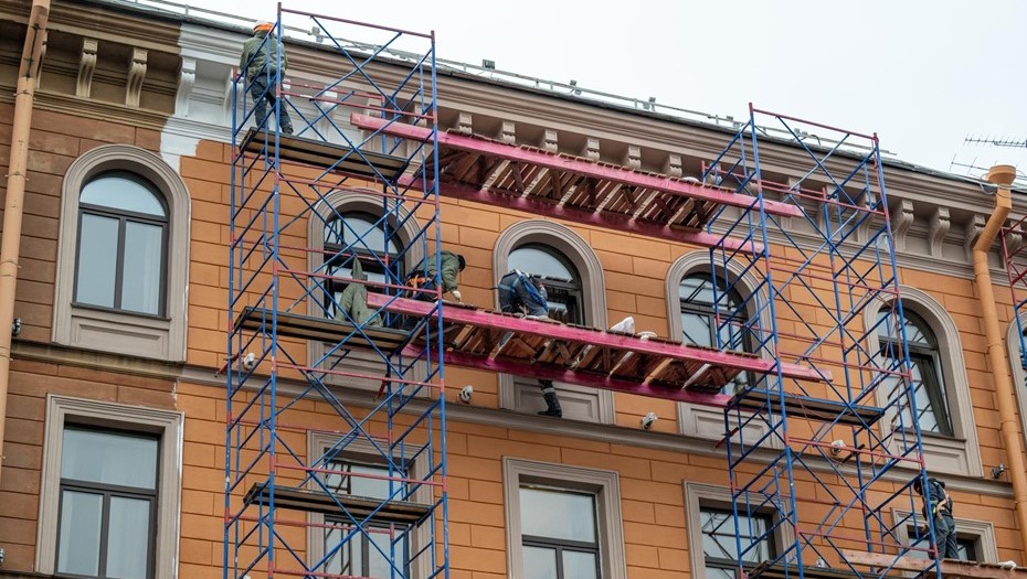 Рабочие стоят на строительных лесах и ремонтируют и красят фасад отеля Астория. Рабочие стоят на строительных лесах и ремонтируют и красят фасад отеля Астория.