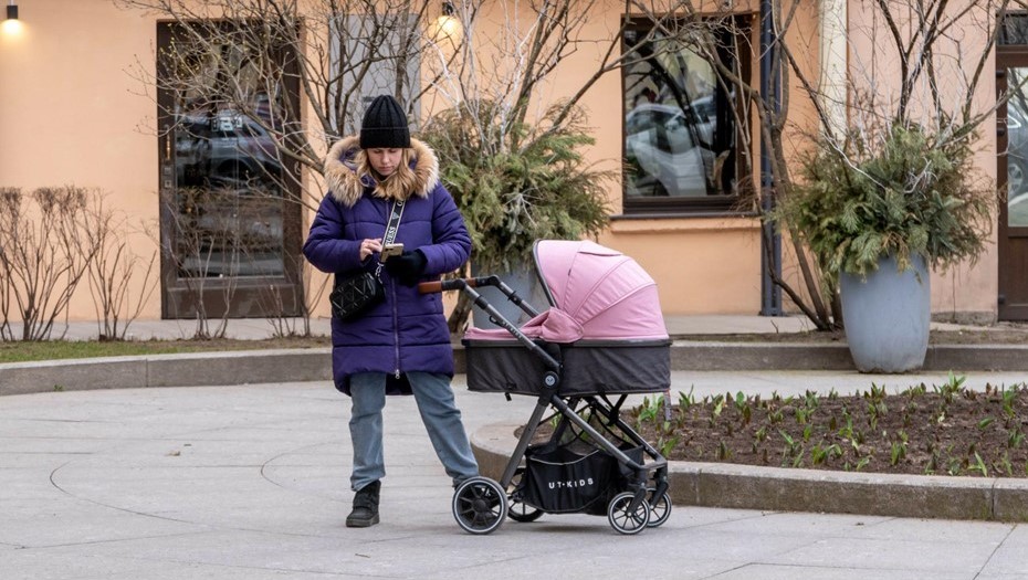 Молодая женщина с коляской стоит в сквере на улице Пестеля.