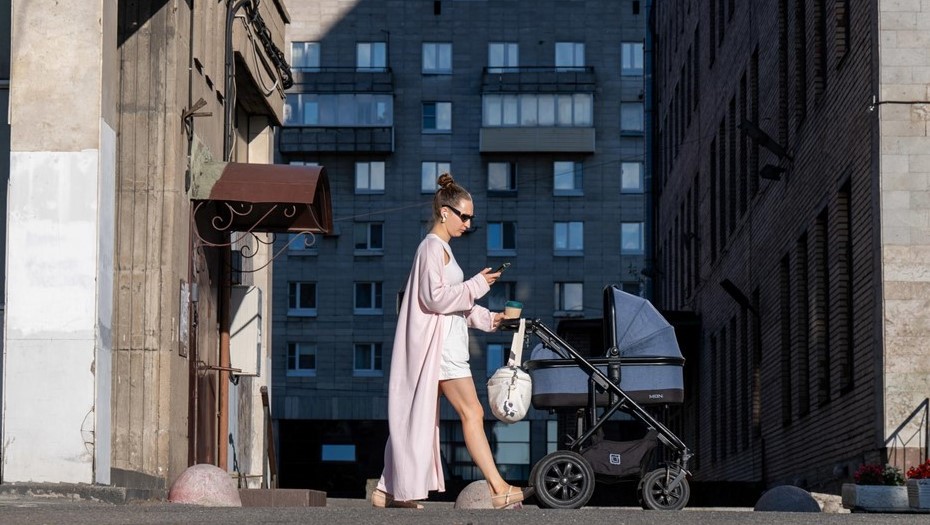 Женщина идет по тротуару и катит детскую коляску. Женщина идет по тротуару и катит детскую коляску.