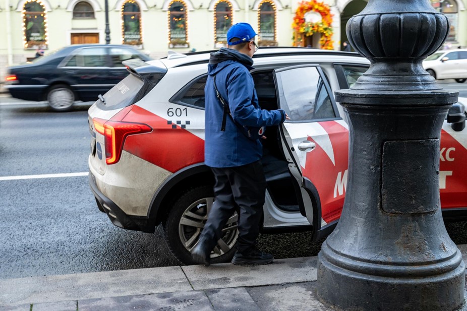 Пассажир садится в автомобиль такси на Невском проспекте.