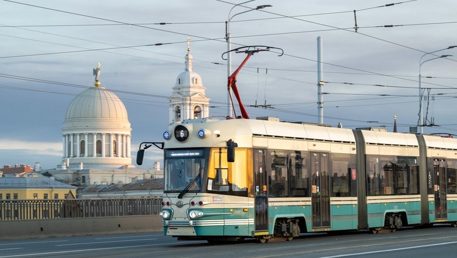 Трамвай "Довлатов" едет по мосту на фоне купола и часовни храма святой Екатерины.