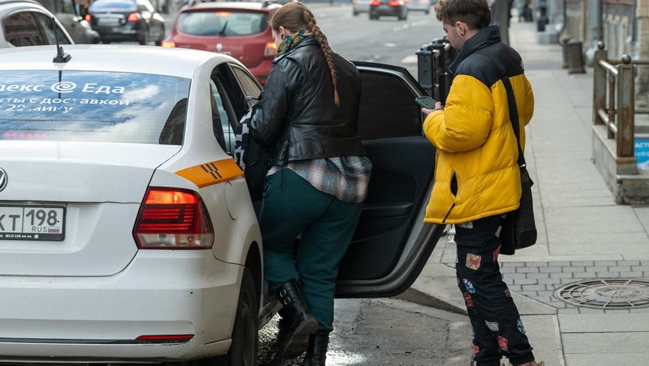 Пассажиры такси садятся в автомобиль.